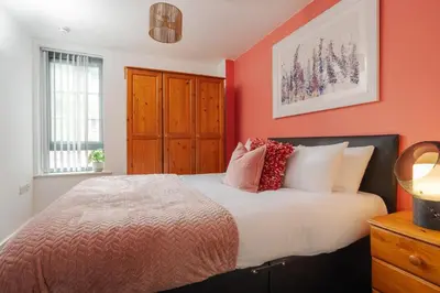 a bedroom with orange walls and a bed with pillows at Central Town Retreat Modern 2BR2BA Apartment Sleeps 7 in Liverpool