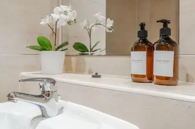 two bottles of soap sitting on a sink in a bathroom at Central Town Retreat Modern 2BR2BA Apartment Sleeps 7 in Liverpool