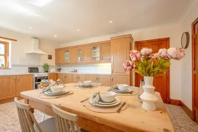 a kitchen with a wooden table with a vase of flowers at Pendle View Gatehouse Lakeside Stay in Pendleton