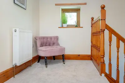 a pink chair in a room with a staircase at Pendle View Gatehouse Lakeside Stay in Pendleton