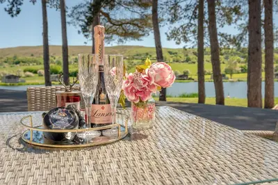 a table with a bottle of wine and flowers on it at Pendle View Gatehouse Lakeside Stay in Pendleton