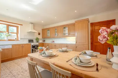 a kitchen with a large wooden table with chairs at Pendle View Gatehouse Lakeside Stay in Pendleton