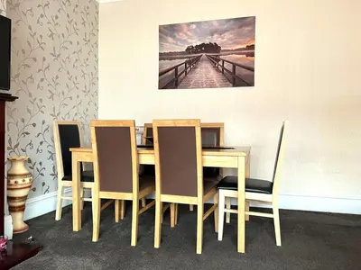 a dining room table and chairs with a painting on the wall at Stylish and Spacious two-bedroom Apartment in Blackpool