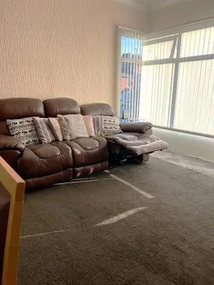 a brown leather couch in a room with a window at Stylish and Spacious two-bedroom Apartment in Blackpool