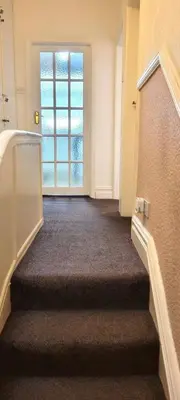 a hallway with a staircase with a door and a window at Stylish and Spacious two-bedroom Apartment in Blackpool
