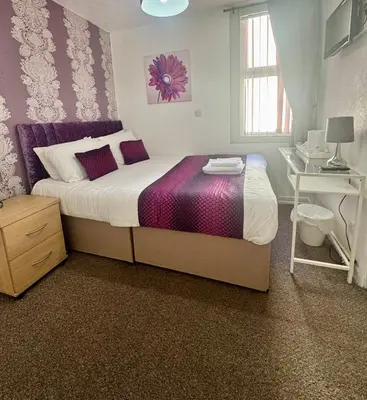a bedroom with a large bed and a desk at On The Beach Hotel in Blackpool