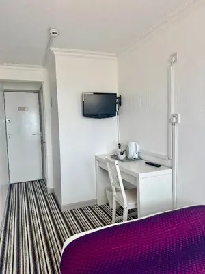 a hotel room with a desk and a tv on the wall at On The Beach Hotel in Blackpool