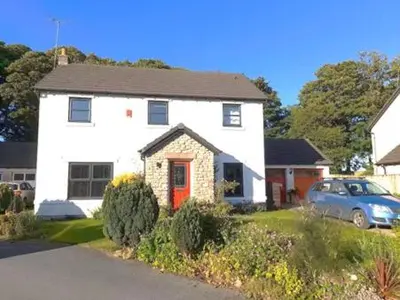 a white house with a red door in a yard at Double room, living space and bathroom, in a family home, near Ulverston in Pennington