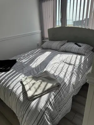 a bedroom with a bed with striped sheets and a window at Lynton apartments in Blackpool