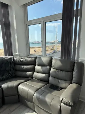 a leather couch in a living room with a large window at Lynton apartments in Blackpool