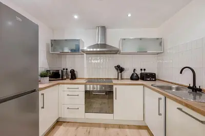 a kitchen with white cabinets and a sink at Baltic Apt II - City Centre with Parking, Sleeps 6 in Liverpool
