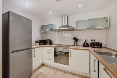 a kitchen with white cabinets and a stainless steel refrigerator at Baltic Apt II - City Centre with Parking, Sleeps 6 in Liverpool