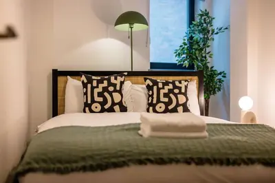 a bedroom with a bed with a green blanket and pillows at Baltic Apt II - City Centre with Parking, Sleeps 6 in Liverpool