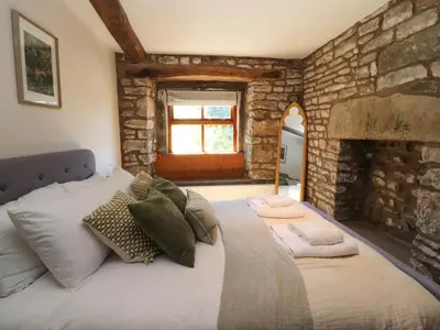 a bedroom with a large bed with a stone wall at Sunnybrook Cottage in Lancaster