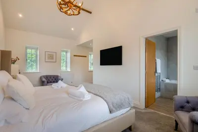 a white bedroom with a bed and two chairs at 3 Bed in West Bradford oc-g32102 in West Bradford