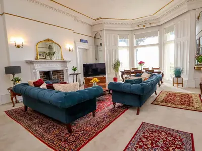 a large living room with blue couches and a fireplace at Ismay Lounge Apartment- Titanic Interest in Liverpool