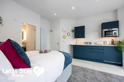 a bedroom with a large bed and a kitchen at Morecambe Bay Stays in Morecambe