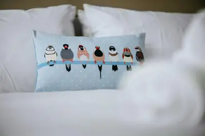 a group of penguins sitting on a pillow on a bed at The Carriage House at the Talbot in Lytham St Annes