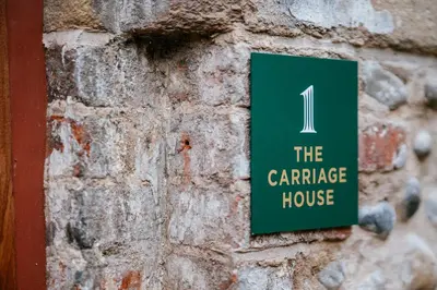 a green sign on a brick wall with the carriage house at The Carriage House at the Talbot in Lytham St Annes