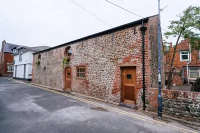a brick building with wooden doors on a street at The Carriage House at the Talbot in Lytham St Annes