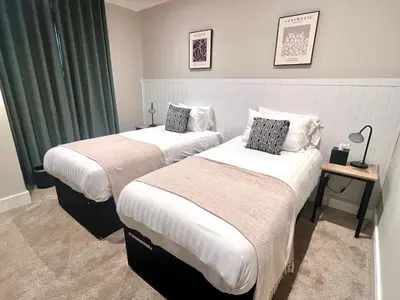 two beds in a hotel room with green curtains at Pleasure Beach Apartments by Central Beach Leisure in Blackpool