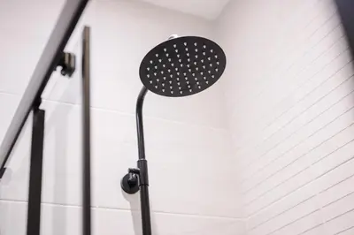 a shower head in a bathroom with a white wall at Pleasure Beach Apartments by Central Beach Leisure in Blackpool