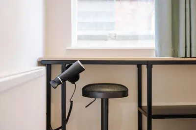 a desk with a stool under a table with a microphone at Pleasure Beach Apartments by Central Beach Leisure in Blackpool