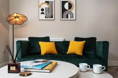 a living room with a green couch with yellow pillows at Pleasure Beach Apartments by Central Beach Leisure in Blackpool