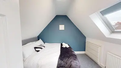 a bedroom with a bed with a blue wall at For Workers 10 Mins to City 5 TVs and Parking in Liverpool