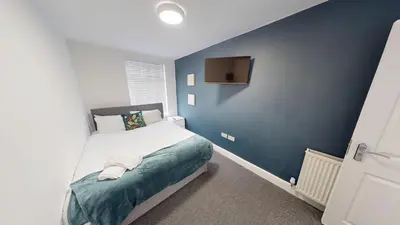a bedroom with a bed with a blue wall at For Workers 10 Mins to City 5 TVs and Parking in Liverpool