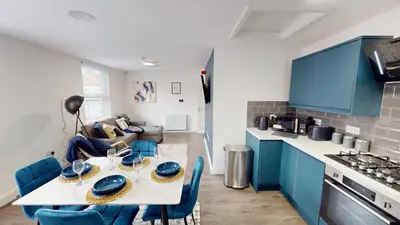 a kitchen and living room with a table and blue cabinets at For Workers 10 Mins to City 5 TVs and Parking in Liverpool