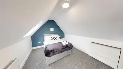 a bedroom with a bed with a blue accent wall at For Workers 10 Mins to City 5 TVs and Parking in Liverpool