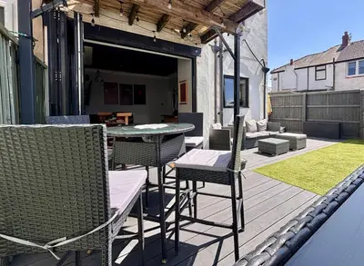 a patio with a table and chairs on a deck at Crescent House, Pleasure Beach in Blackpool