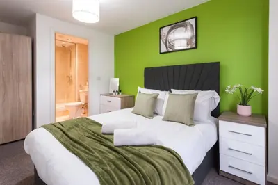 a green bedroom with a large bed with a green wall at Modern City Apartment By Chalefor Living in Liverpool