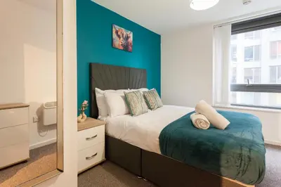a bedroom with a bed with a blue wall at Modern City Apartment By Chalefor Living in Liverpool