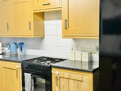 a kitchen with a stove and wooden cabinets at Room 2 Shared House in Bootle in Litherland