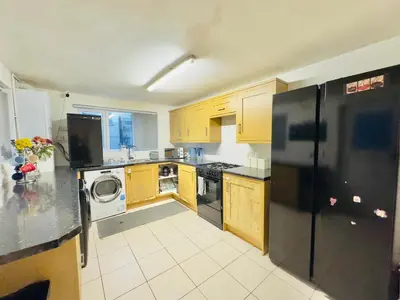 a kitchen with wooden cabinets and a black refrigerator at Room 2 Shared House in Bootle in Litherland