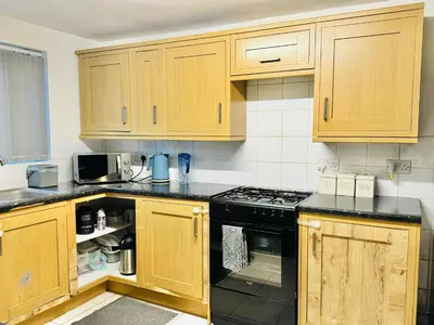 a kitchen with wooden cabinets and black appliances at Room 2 Shared House in Bootle in Litherland