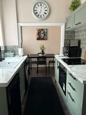 a kitchen with a clock on the wall and a table at Anfield Home - Sleeps 7 - 1 min walk to Stadium! in Liverpool