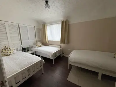 a bedroom with two beds and a window at Anfield Home - Sleeps 7 - 1 min walk to Stadium! in Liverpool