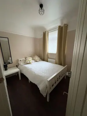 a bedroom with a white bed with pillows and a window at Anfield Home - Sleeps 7 - 1 min walk to Stadium! in Liverpool