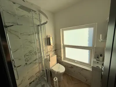 a bathroom with a shower and a toilet and a window at The Anfield Loft in Liverpool