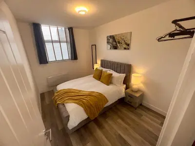 a bedroom with a bed with yellow blankets and a window at 2 Bed Preston City Centre - Sleeps 4 with 1 Free Parking Space in Preston