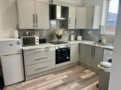 a kitchen with white cabinets and a sink and a microwave at 2 Bed Preston City Centre - Sleeps 4 with 1 Free Parking Space in Preston
