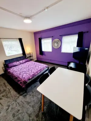 a purple room with a bed and a table at Birkenhead House in Bidston