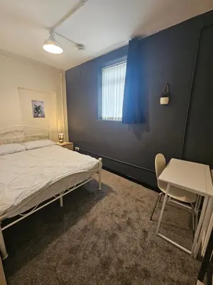 a bedroom with a bed and a table and a window at Birkenhead House in Bidston