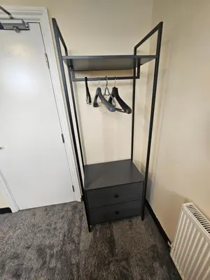 a black cabinet with hangers in front of a door at Birkenhead House in Bidston