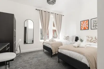a bedroom with two beds and a mirror and a window at Modern 4bedroom City Home Near LFC in Liverpool