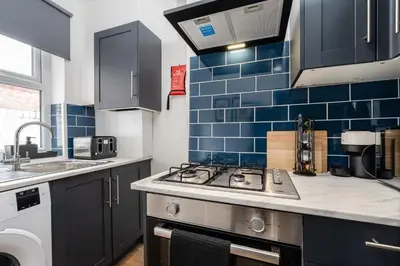 a kitchen with blue tiles on the wall at Modern 4bedroom City Home Near LFC in Liverpool