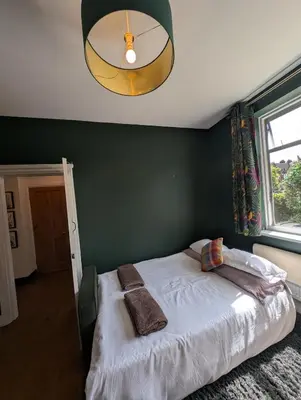 a bedroom with a bed with a green wall at Luxury 3 bed house with off road parking for 2 cars, garden, 10 minutes from city-centre in Liverpool